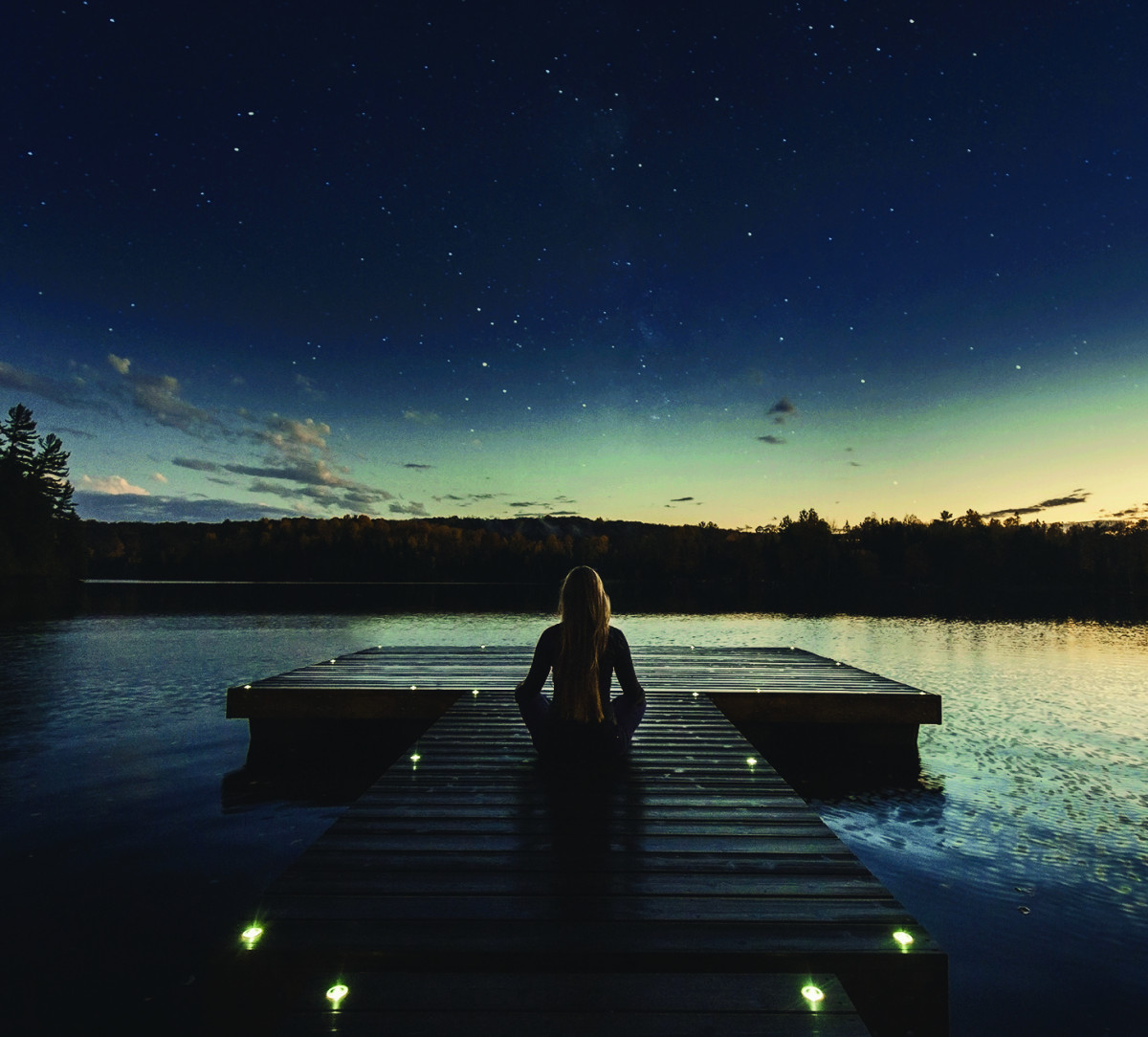 Woman meditating on top of a dock