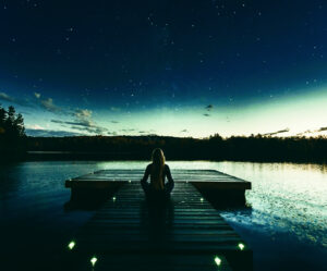 Woman meditating on top of a dock