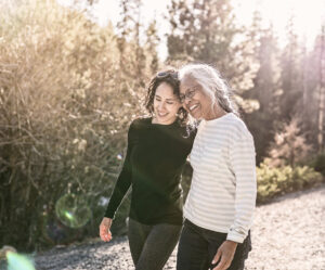 Two woman smiling as they walk down a nature trail