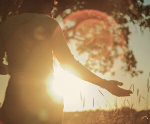 Woman standing in a field at sunset