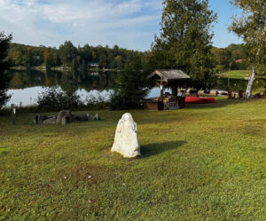 Large rock in a field with a lake in the distance