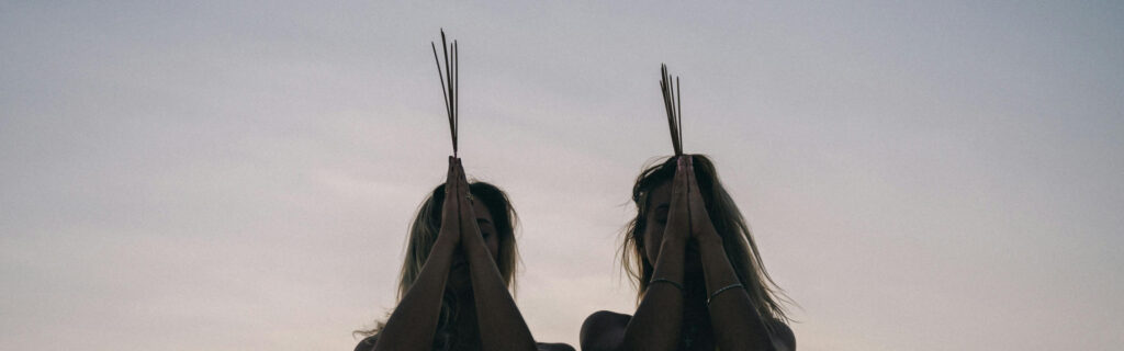 Two woman holding reeds to their head