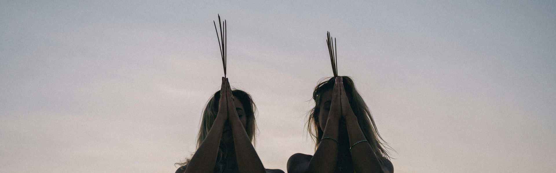 Two woman holding reeds to their head