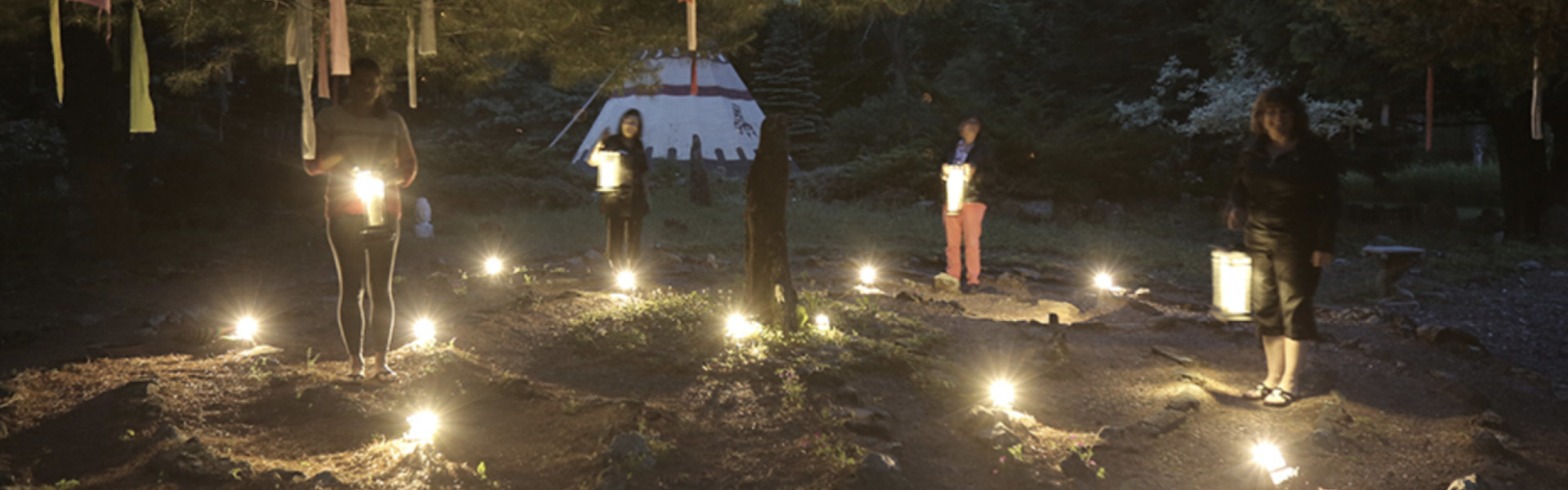Women standing with lanterns in a clearing