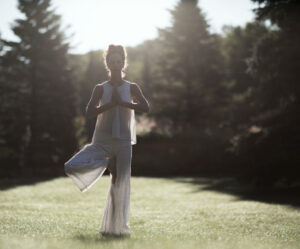 Woman in a yoga pose in the middle of a grass field